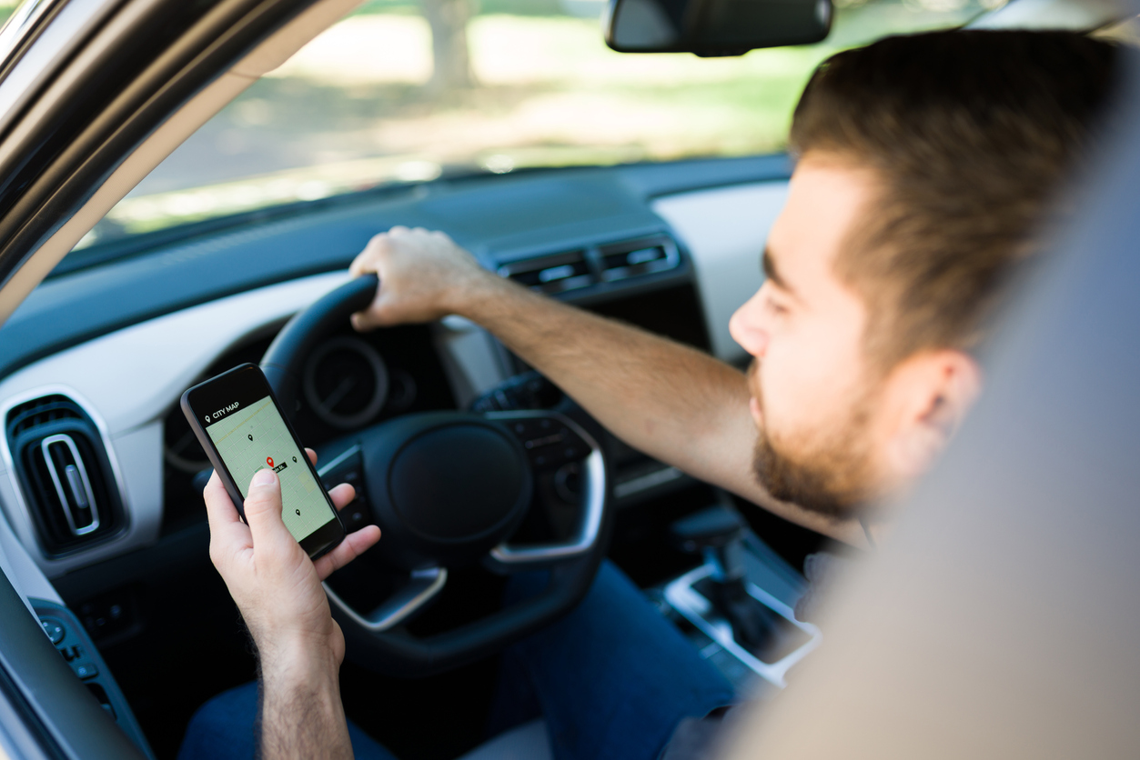 Um homem aparece dirigindo um carro, enquanto segura o volante com uma mo na outra ele segura o celular e aparece um mapa virtual na tela, indicando passageiros para ele transportar